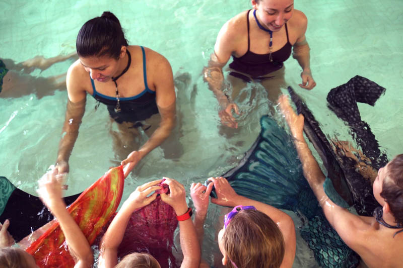 Children learning to put on a mermaid tail