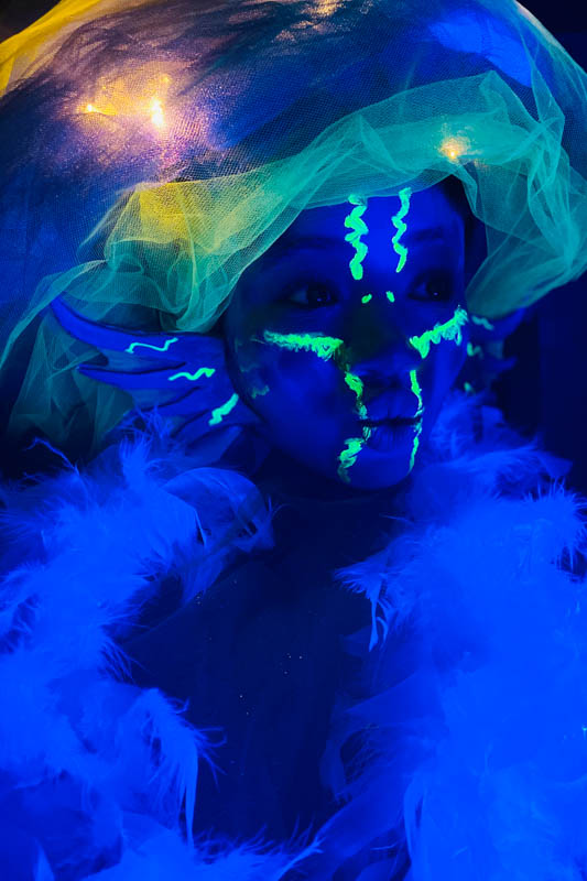 girl dressed as a glowing sea creature under a black light