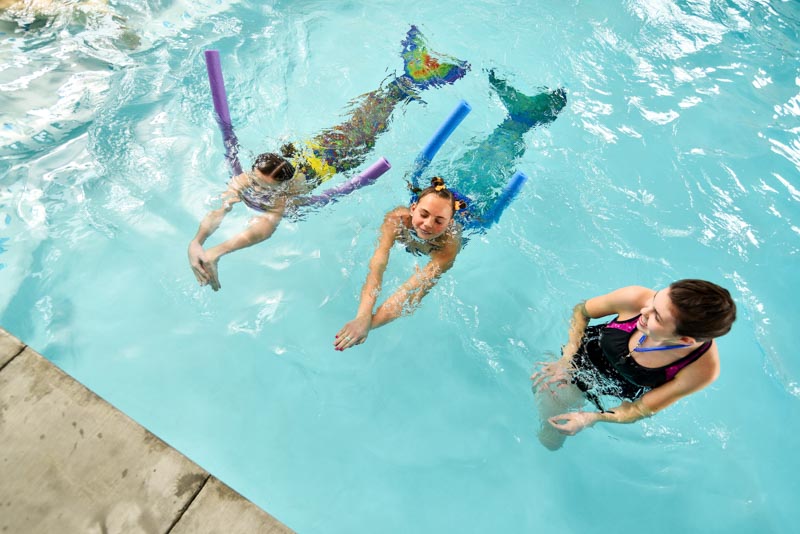 girls practicing mermaid tail swimming at a mermaid university class