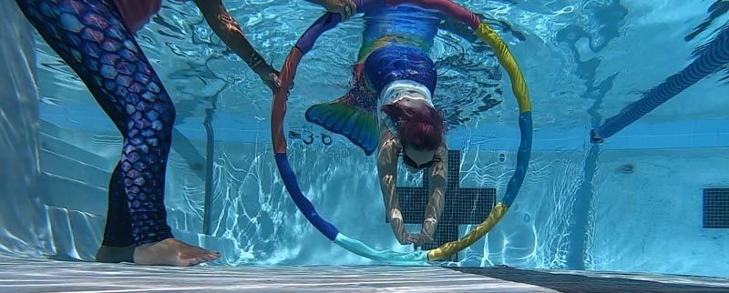 Molly swimming through hoops in her mermaid class.