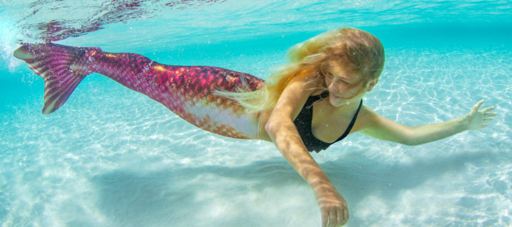 A girl swimming in the Bronzed Ruby mermaid tail.