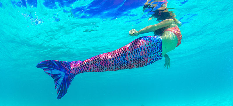 A girl swimming in the Sea Glass mermaid tail.