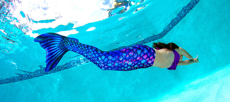 A girl swimming in the Ice Dragon mermaid tail of the month.