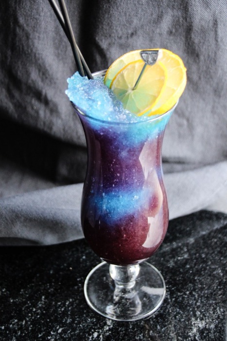 this purple and blue slushie with lemon slices looks like a galaxy in a glass