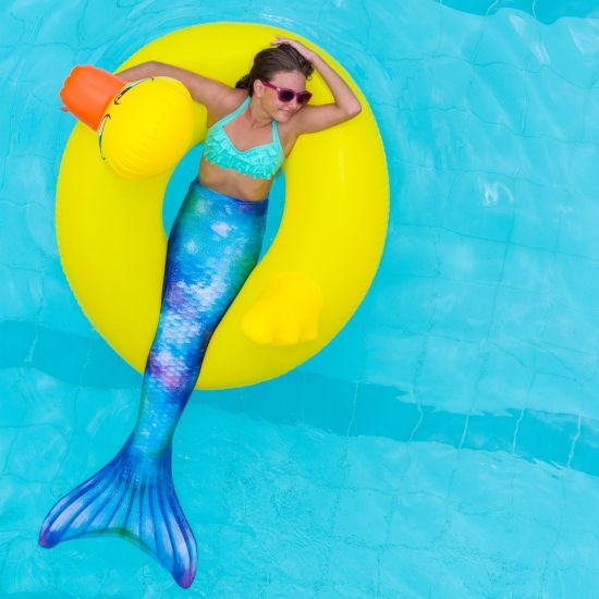 girl in the Fin Fun Watercolor waves tail, floating on an inflatable duck pool toy