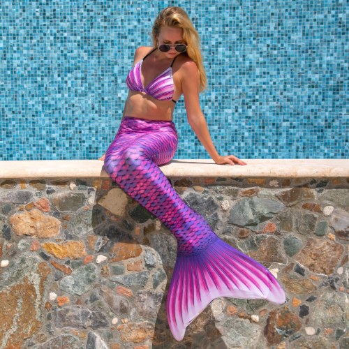 a woman sitting on a wall and spending her summer in a mermaid tail