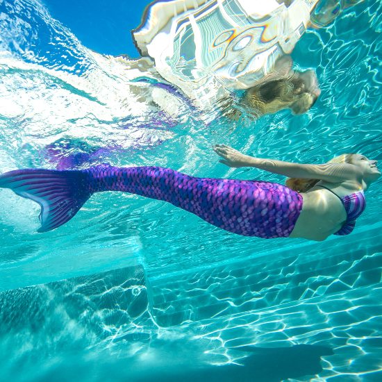 girl swimming underwater in a purple mermaid tail