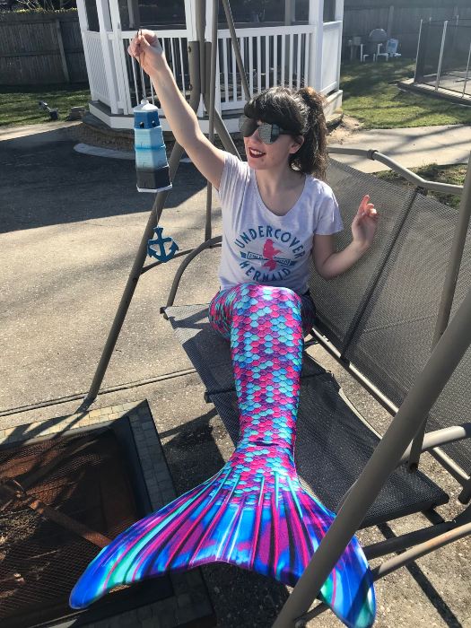 girl in the Berry Splash Limited Edition mermaid tail sitting on a swing holding up a lighthouse ornament