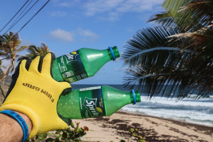 someone holding up two soda bottles that littered the beach