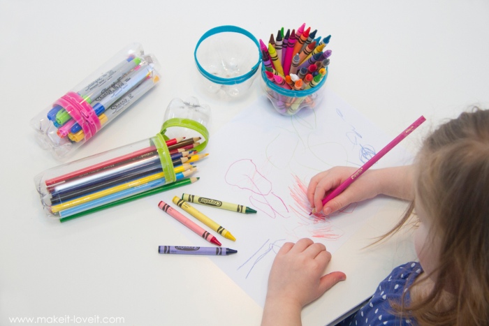 a young girl drawing with pencils and crayons, which are in recycled plastic bottle cases