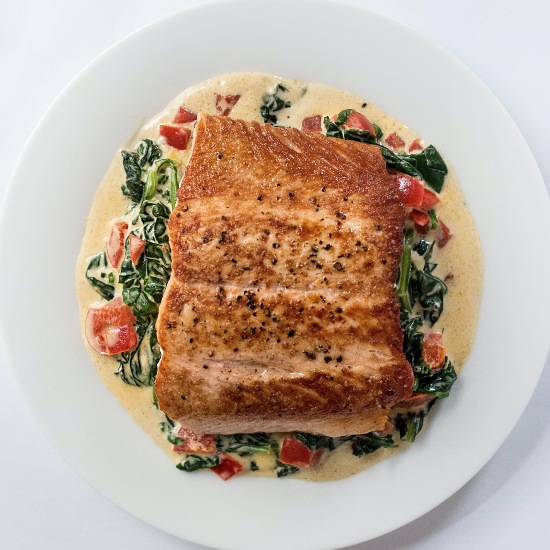 a beautiful plate of fish florentine from above: seared fish on a creamy sauce with spinach and pepper