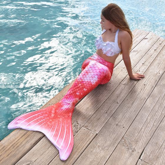 a girl sitting on a wooden dock in the Coral Cloud tail, another available Retro Mermaid Tail