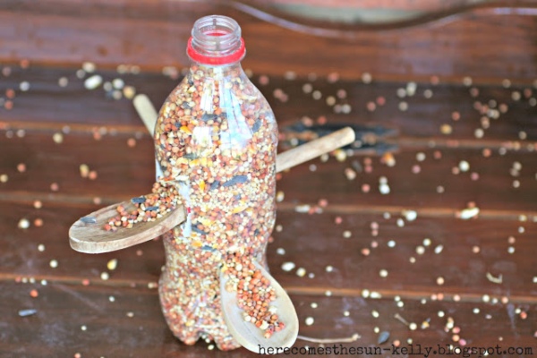 a reused plastic bottle full of bird seed with wooden spoons for perches