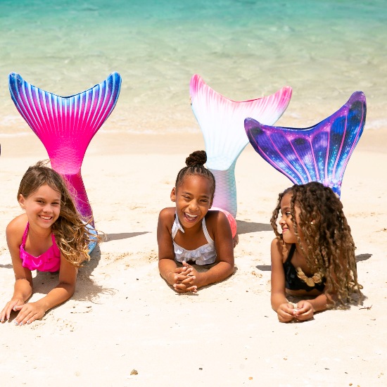 three mermaids on the beach wearing three different Limited Edition mermaid tails