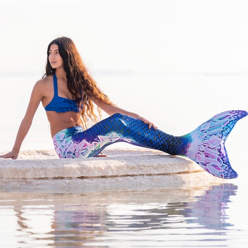 A mermaid poses in an indigo mermaid tail with crystals on the sides and fluke.