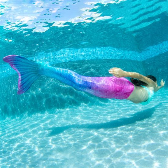 A girl swims underwater in the pink and blue Fiji Fantasy mermaid tail.