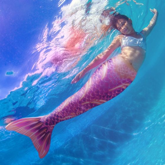 a girl swimming underwater in the pink and yellow Deep Sea Rave Limited Edition tail