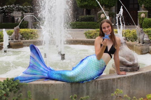 Mermaid Kylie posing by a fountain while wearing the Pacific Pearl Altantis mermaid tail.