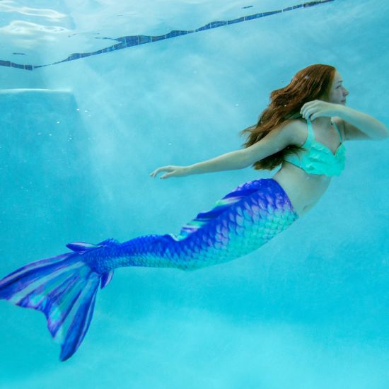 a magical underwater shot of a mermaid in a mermaid tail with side fins