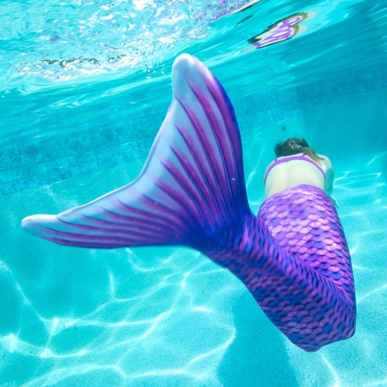 a young mermaid swimming underwater in a purple Fin Fun mermaid tail from the Mermaidens line
