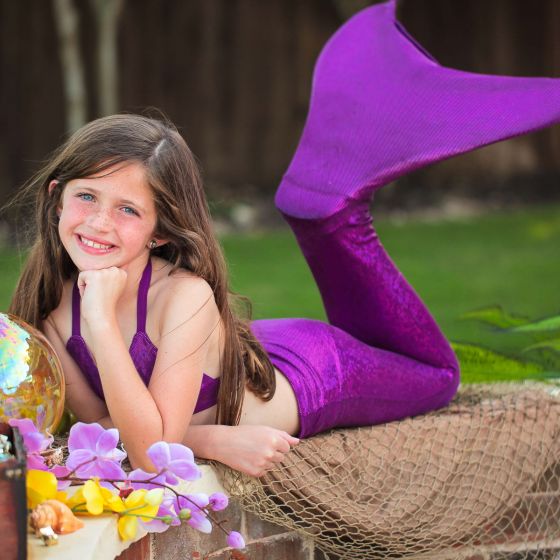 a young girl posing for a photoshoot in a purple Sparkle mermaid tail by fin fun