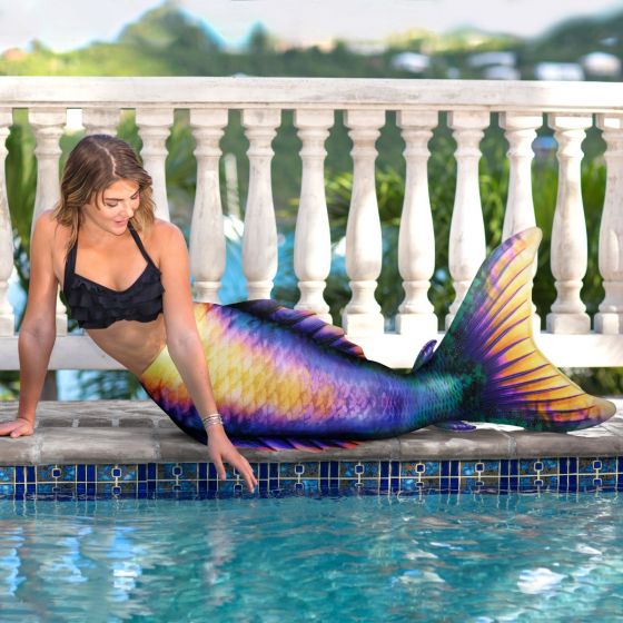 a mermaid laying on her side next to the pool in an atlantis mermaid tail